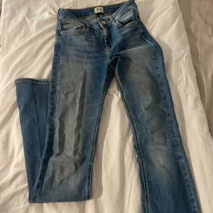 Blå flared jeans från ONLY, stl 34, S - Säljer ett par klassiska blå flared jeans från ONLY i storlek 34. Jeansen har låg midja, fem fickor och snygga slitningar framtill. Tillverkade i stretchig denim för en bekväm passform 