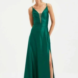 Grön långklänning med slits - Snygg grön långklänning med djup v-ringning och tunna axelband. Klänningen har en hög slits på ena sidan och är gjord i ett glansigt material som ger en lyxig känsla. Perfekt för bal eller festliga tillfällen. Köpt på Zalando 2022 men använd endast en gång. Uppsydd för att passa mig, jag är 164 och när jag hade ett par klackar på mig blev den perfekt i längden! 