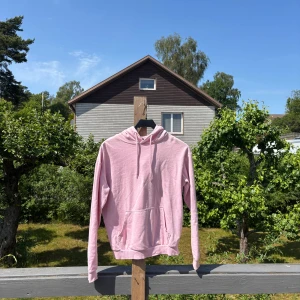 Ljusrosa hoodie i ekologisk bomull - Säljer en ljusrosa hoodie från C i ekologisk bomull. Tröjan har huva med snörning, magficka och långa ärmar. Perfekt för dig som gillar en chill och enkel stil. Passar dig som vill ha en mjuk och skön hoodie till vardagen. Passar storlek S 