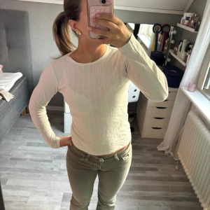 Vit ribbad långärmad tröja - Säljer en vit långärmad tröja med ribbad struktur. Tröjan har en rund halsringning och sitter tajt mot kroppen, perfekt för en clean och enkel look. Passar till allt och är superenkel att styla med olika outfits. 💕