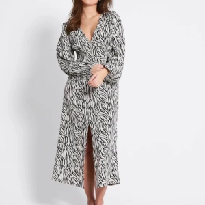 Zebramönstrad långklänning omlott - Snygg långklänning med zebramönster i svart och vitt. Klänningen har omlottmodell, v-ringning och långa ärmar. Perfekt för dig som vill sticka ut med en trendig look och gillar djurmönster. Från lager 157, helt slutsåld!! 450 kr 