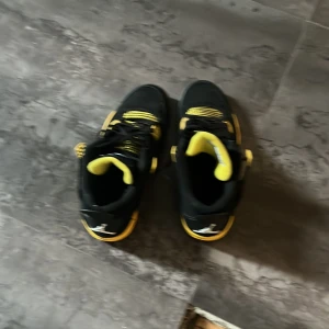 Gula thunders jordans replika  - Säljer ett par svarta sneakers med gula detaljer från Jordan. Skorna har snörning och den klassiska Jumpman-loggan på sulan. Perfekta för dig som vill sticka ut med färg och sportig stil,