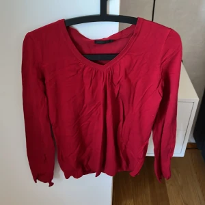 Röd v-ringad tröja - Säljer en röd långärmad tröja från Stockh LM i storlek M. Tröjan har v-ringning och är i ett mjukt, tunt material som passar perfekt till vardags. Enkel och stilren design.