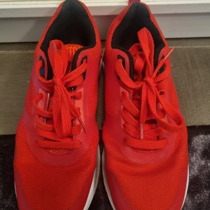 Röda sneakers - Säljer ett par röda sneakers från Stadium i storlek 38. Skorna har snörning, vit sula och svarta detaljer på insidan. Perfekta för dig som vill ha ett par färgstarka och sportiga skor till vardags. Sparsamt använda!