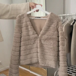 Beige fluffig kofta - Supermjuk och fluffig beige kofta med lång ärm och öppen framtill. Perfekt för lager-på-lager och ger en mysig känsla. Passar till både jeans och kjol för en chill look.