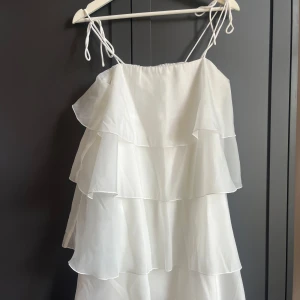 Vit organza volangklänning från Gina Tricot - Säljer en söt vit mini-klänning från gina använt en gång o köptes förra året i maj vara bara hängt i mitt rum så kan säga att den är helt ny😚