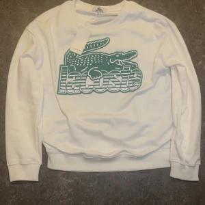 Lacoste sweatshirt - Säljer en vit sweatshirt från Lacoste med stor grön krokodil.