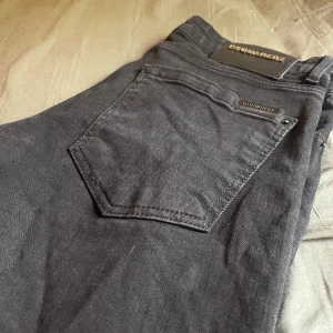 Svarta jeans från Dsquared2 - Säljer ett par svarta jeans från Dsquared2 med klassisk femficksdesign och snygga detaljer. Byxorna har metallogo på bakfickan och knappstängning framtill. Perfekta för dig som gillar stilrena och exklusiva jeans.