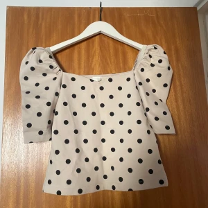 Beige topp med puffärmar och svarta prickar - Säljer denna söta topp då den tyvvär var för liten för mig! Den är i ett stretchigt material och aningen tjockare.