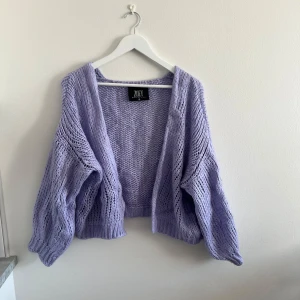 Ljuslila stickad kofta från Zoey - Superfin ljuslila stickad kofta med oversized passform och grovstickat mönster. Koftan har långa ärmar och är perfekt att slänga på sig för en mysig look. Snygg att styla till både jeans och klänning.