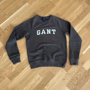 Mörkgrå sweatshirt från GANT - Säljer en brun sweatshirt från GANT med vit logotyp på bröstet. 
