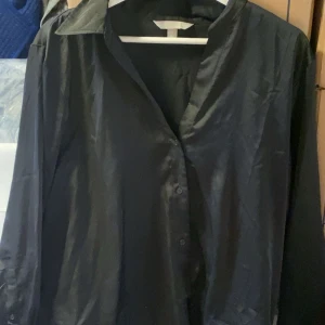 Svart klassisk skjorta - Säljer en svart skjorta med klassisk krage och knäppning framtill. Skjortan har lång ärm och en stilren, tidlös design som passar till många olika outfits. Perfekt för dig som gillar en clean och enkel look.