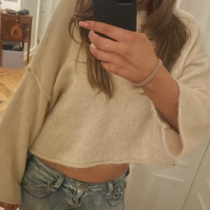 Beige croppad stickad tröja från Zara - Säljer en beige croppad stickad tröja med lång ärm och avslappnad passform. Perfekt till jeans och enkel att styla för en chill look. Tröjan har en mjuk känsla och är lite oversized.