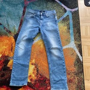 Blå Replay jeans straight fit - Säljer ett par klassiska blå jeans från Replay med raka ben och normal passform. Jeansen har fem fickor, dragkedja och knapp i midjan samt Replay-logga på fickan. Perfekta till vardags och lätta att matcha med olika stilar.