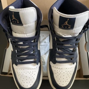 Air Jordan 1 Mid - Storlek 42,5, finns lite creases, ett ganska litet rep hål, har försökt rengöra dem så gott det går men det finns lite gult och lite brunt på vissa ställen på det, inte jätte mycket men mest i fram på den vita sulan. Att mötas går också bra. 