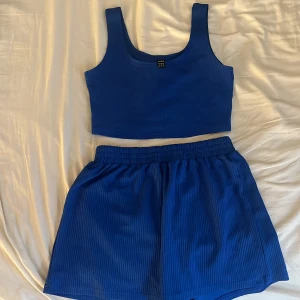 Blå sett - Säljer ett par blå ribbade shorts med elastisk midja. Perfekta för sommaren och riktigt sköna att ha på sig. Ingår även en matchande topp till i samma färg och samma material
