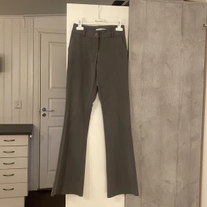 Grå konstymbyxor från Design Si - Säljer ett par grå byxor från Design Si i storlek XS. Snygga bootcut låtmidjade/mid waist