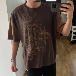 Brun Y2K tshirt - Jag säljer denna t shirt som ALDRIG använts, har bara provat den. Den är från collusion och har et häftigt tryck, färgen är brunare och finare IRL. Det är stl S men den sitter ganska oversized