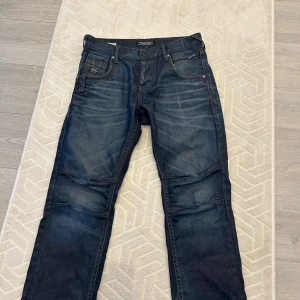 Mörkblå jeans från Jack & Jones - Säljer ett par mörkblå jeans från Jack & Jones Core med klassisk femficksdesign och snygga slitningar. Jeansen har normal passform och raka ben, perfekta till vardags. Använda 1-2 gånger. Som ny. Midjan - 30 Längden - 31