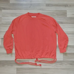 Orange tröja från Black Story - Säljer en snygg orange tröja från Black Story i storlek S. Tröjan har långa ärmar och en unik snörning i nederkanten som ger en cool look. Perfekt för att liva upp garderoben! 🧡