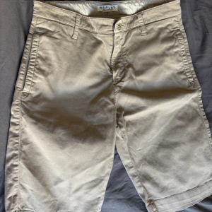 Beige shorts från Replay - Snygga beige shorts från Replay med dragkedja och knapp framtill. Perfekta för sommardagar med sin klassiska stil och bekväma passform. Tillverkade i ett slitstarkt material som ger en stilren look.