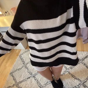 Svart och vit randig tröja från Gina Young - Säljer en supersnygg randig stickad tröja från Gina Young med ett snitt på sidorna då jag inte får användning till den. Tycker den är skön i materialet. Storlek 146/152 men tycker jag den passar även upp till 170! Jättesnygg med ett par jeans till!!💓💓