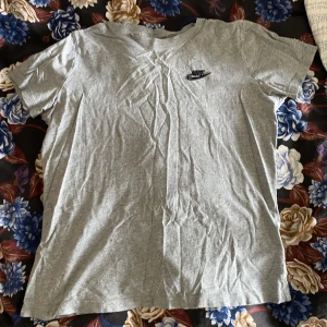 Grå Nike T-Shirt - Grå Nike T-shirt med svart märke på bröstet, lite cropped