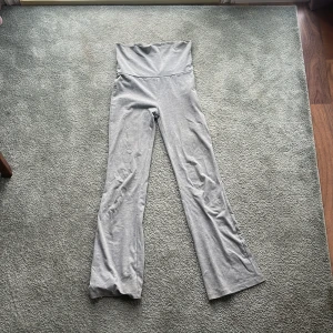 Grå byxor från Gina Tricot - Snygga grå byxor från Gina Tricot med låg midja och bootcut-stil. Perfekta för en avslappnad look. Tillverkade i ett mjukt och bekvämt material som ger en skön passform.