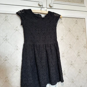 Svart spetsklänning från H&M - Säljer en elegant svart spetsklänning från H&M. Klänningen har korta ärmar och en dragkedja i ryggen för enkel påklädning. Perfekt för speciella tillfällen med sin fina spetsdesign. Använd ok många gånger. STORLEK=146cl