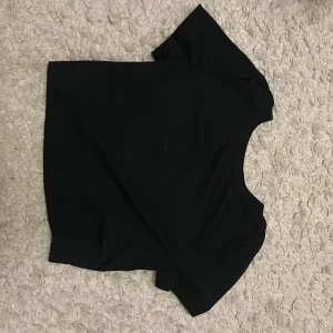 Svart kortärmad topp - Snygg svart kortärmad/mag tröja, med en öppen rygg. Kan matchas med olika outfits.