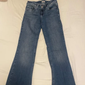 Blå bootcut jeans - Snygga blå bootcut jeans med klassisk femficksdesign och dekorativa sömmar på bakfickorna från Nelly i storlek eu 36