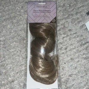 Sweetlux Clip In Wavy Extensions - Sweetlux Clip In Wavy Extensions i en vacker brun nyans. Dessa högkvalitativa syntetiska hårförlängningar är perfekta för att ge ditt hår extra volym och längd. Enkel att använda med klämfästen för en snabb och smidig applicering.