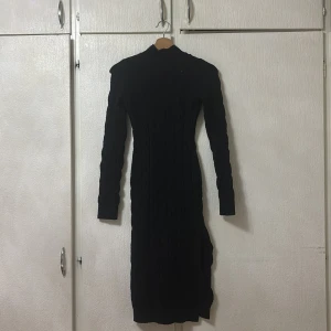 Svart stickad klänning från PrettyLittleThing - Snygg svart stickad klänning från PrettyLittleThing i storlek XS. Klänningen har en lång design med långa ärmar och ett stilrent mönster. Perfekt för kyligare dagar.