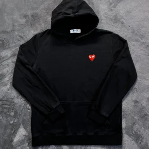 CDG Hoodie - Säljer en stilren svart hoodie från Comme des Garçons med det ikoniska röda hjärtat med ögon på bröstet. Storlek XL men passar L/M, Skick 8/10 är använd. Pris går att diskutera✅