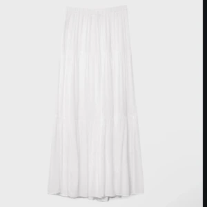 Vit långkjol - Elegant vit långkjol med en luftig och flödande design. Perfekt för varma dagar med sin lätta och bekväma passform. Kjolen har en elastisk midja för extra komfort. Använd sällan! ❤️Jag köpte min i London för 400kr!
