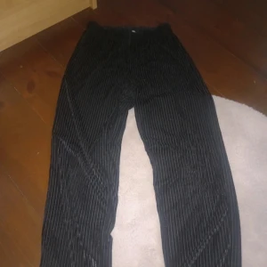 Svarta mjukisbyxor - Snygga svarta mjukisbyxor med diskret randigt mönster. Perfekta för en stilren look. Byxorna har en normal passform och är tillverkade i mjukt manchestertyg.