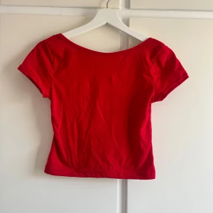 Röd croppad topp - Säljer en snygg röd croppad topp med korta ärmar och öppen rygg. 