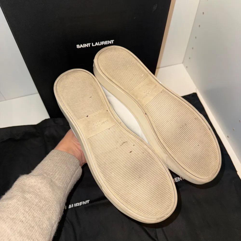 Snygga vita sneakers från Saint Laurent med klassisk design och diskret logga på sidan. Skorna har snörning och en bekväm sula, perfekta för en stilren look.. Kengät.