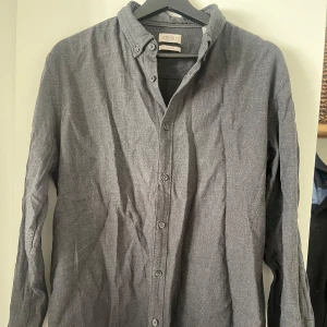 Grå overshirt från Esprit - Snygg grå skjorta från Esprit i regular fit. Skjortan har långa ärmar och knappar framtill. Perfekt för en stilren look. Använd som overshirt med en vit tshirt för än klassisk look. Nypris: 799kr