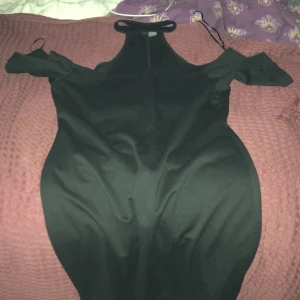 Svart omlottklänning från Divided - Snygg svart kortklänning från Divided med omlott-design och offshoulder-ärmar. Klänningen har en smickrande tight passform och är tillverkad i mjukt polyester-material. Perfekt för dig som gillar stilrena och trendiga plagg med en modern touch.