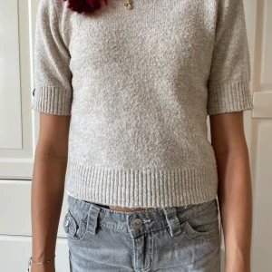 Beige stickad tröja från LMTD - Säljer en beige stickad tröja från LMTD i storlek XS. Tröjan har korta ärmar och ribbade muddar vid ärmslut och nederkant. Den är mjuk och har en enkel, clean look som funkar till jeans eller kjol. Perfekt för dig som gillar neutrala färger och sköna material. Den är lite nottrig men det syns knappt!