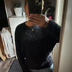 Mörk fluffig stickad tröja H&M - Mysig mörk stickad tröja från H&M med fluffig yta och rund hals. Tröjan har ett ribbat mönster och långa ärmar, perfekt för att hålla värmen. Passar dig som gillar en enkel men ändå trendig look. Stl 158/164 men passar bra som xs.