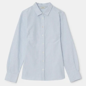 Randig blå skjorta från Arket - Snygg randig skjorta från Boomerang i färgen ice blue. Skjortan har klassisk krage, knappar framtill och långa ärmar med breda manschetter. Tillverkad i ekologisk bomull med smala blå och vita ränder för en fräsch look. Nypris: 1199kr