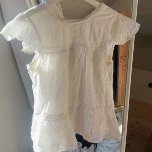 Vit tröja med volangärmar - Säljer en söt vit blus med volangärmar och lätt rynkad struktur. Blusen har rund hals och fina sömdetaljer som ger en bohemisk känsla. Perfekt för varma dagar och enkel att styla.