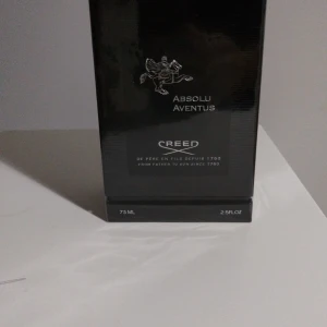 Creed Absolu Aventus 75ml parfym fantastiskt kvalite  - Lyxig parfym Creed Absolu Aventus i svart, stilren förpackning med silverdetaljer och logga. Flaskan rymmer 75ml (2.5 fl oz) och har en exklusiv känsla med signatur på toppen av kartongen. Perfekt för dig som gillar eleganta och klassiska dofter.