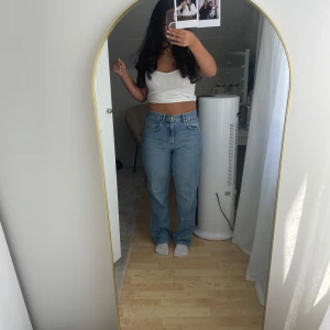 Blå raka jeans med hög midja - Säljer ett par ljusblå jeans med klassisk femficksdesign och hög midja. Jeansen har raka ben och sitter snyggt över höften. Perfekta för dig som gillar en chill och tidlös look. Materialet är robust denim i bomull och passformen är normal.