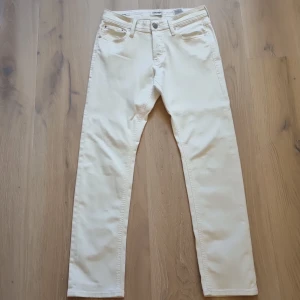 Vita jeans från jack and jones SLIM/GLEEN - Snygga vita jeans från Jack & Jones med klassisk femficksdesign och raka ben. Byxorna har normal passform och är tillverkade i mjuk bomull med lite stretch för extra komfort. Perfekta för dig som gillar stilrena och ljusa jeans. Jeansen är slimfit.