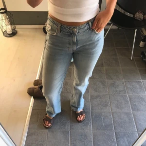 Ljusblå wide jeans från Bikbok - Säljer ett par ljusblå jeans från Bikbok med wide passform och midwaist. Jeansen har klassisk femficksdesign, slitning vid fickan och raka ben. Perfekt för dig som gillar en avslappnad och trendig look.