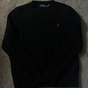 Svart kabelstickad tröja Polo Ralph Lauren - Svart kabelstickad tröja från Polo Ralph Lauren. Perfekt för dig som behöver en tröja nu till hösten-vintern då den håller värmen. Ett bra och skönt materiel. Skick 9/10 Nästan helt ny använd runt 2 gånger. Priset är hugget i sten 
