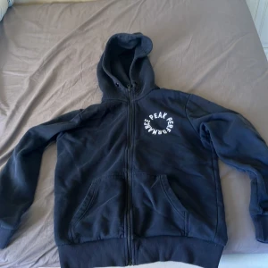 Mörkblå hoodie från Peak Performance - Säljer en mörkblå hoodie från Peak Performance i storlek S. Tröjan har huva, dragkedja framtill och två stora fickor. Materialet är mjuk bomull med fleece på insidan. Logga i vitt på bröstet ger en clean och sportig vibe. Perfekt för chill eller träning.